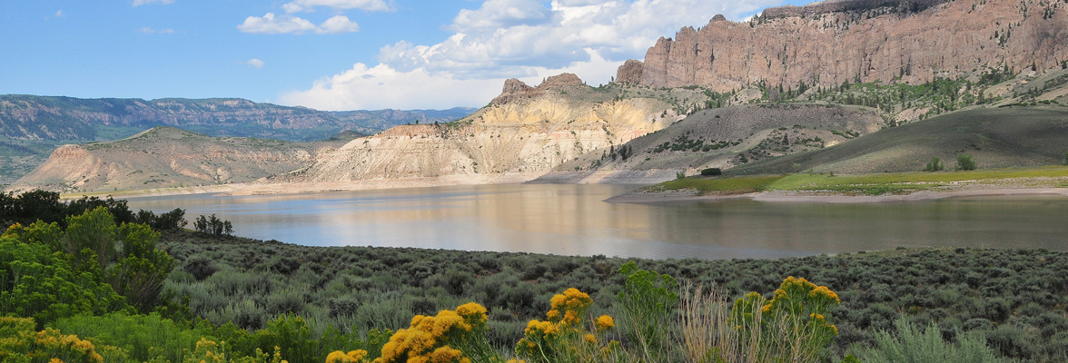 Placid lake surrounded by rocky cliffs and green fields